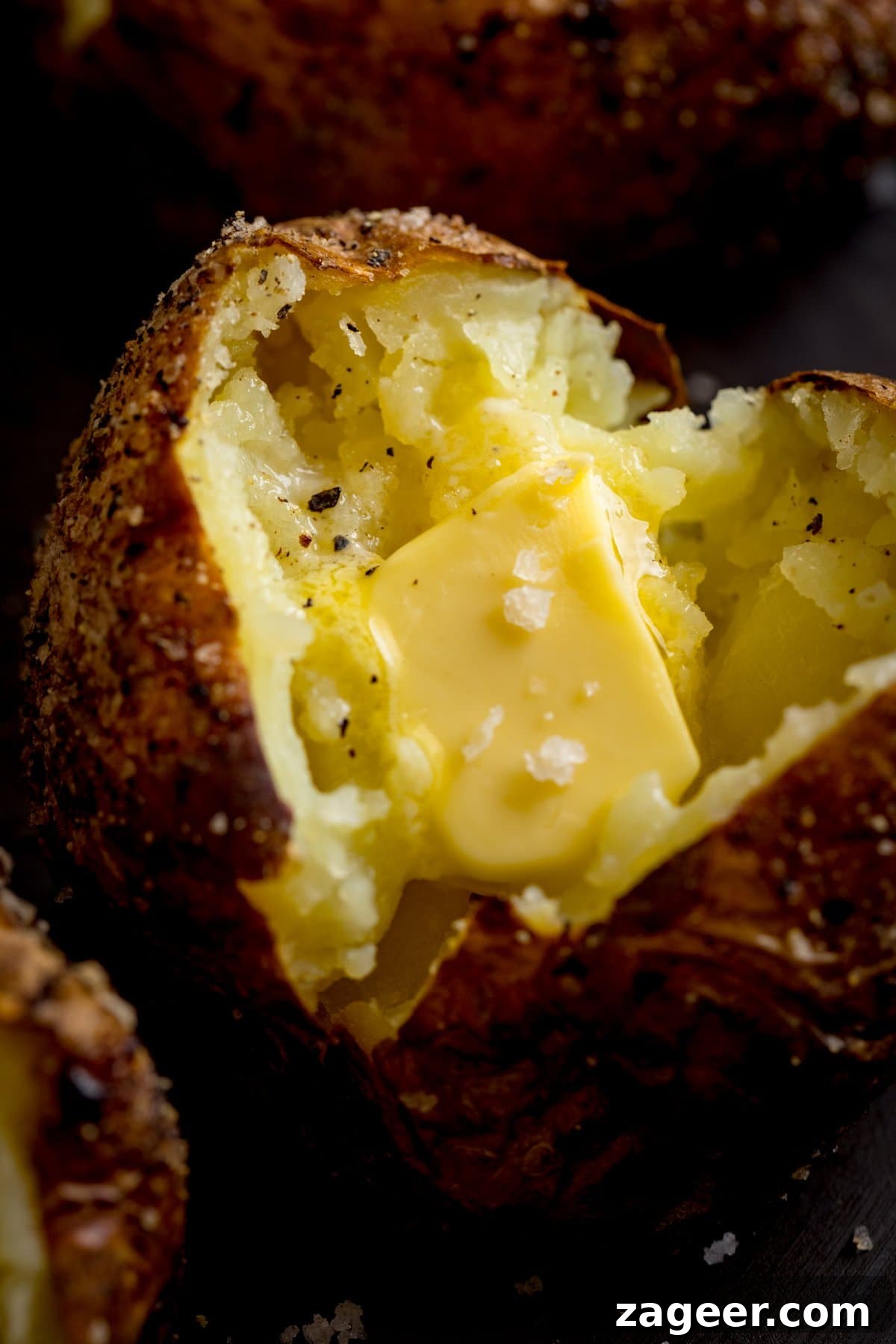 Perfectly Crispy Baked Potato: Foolproof Oven Method 5 Close up image of an open baked potato, filled with a knob of butter.
