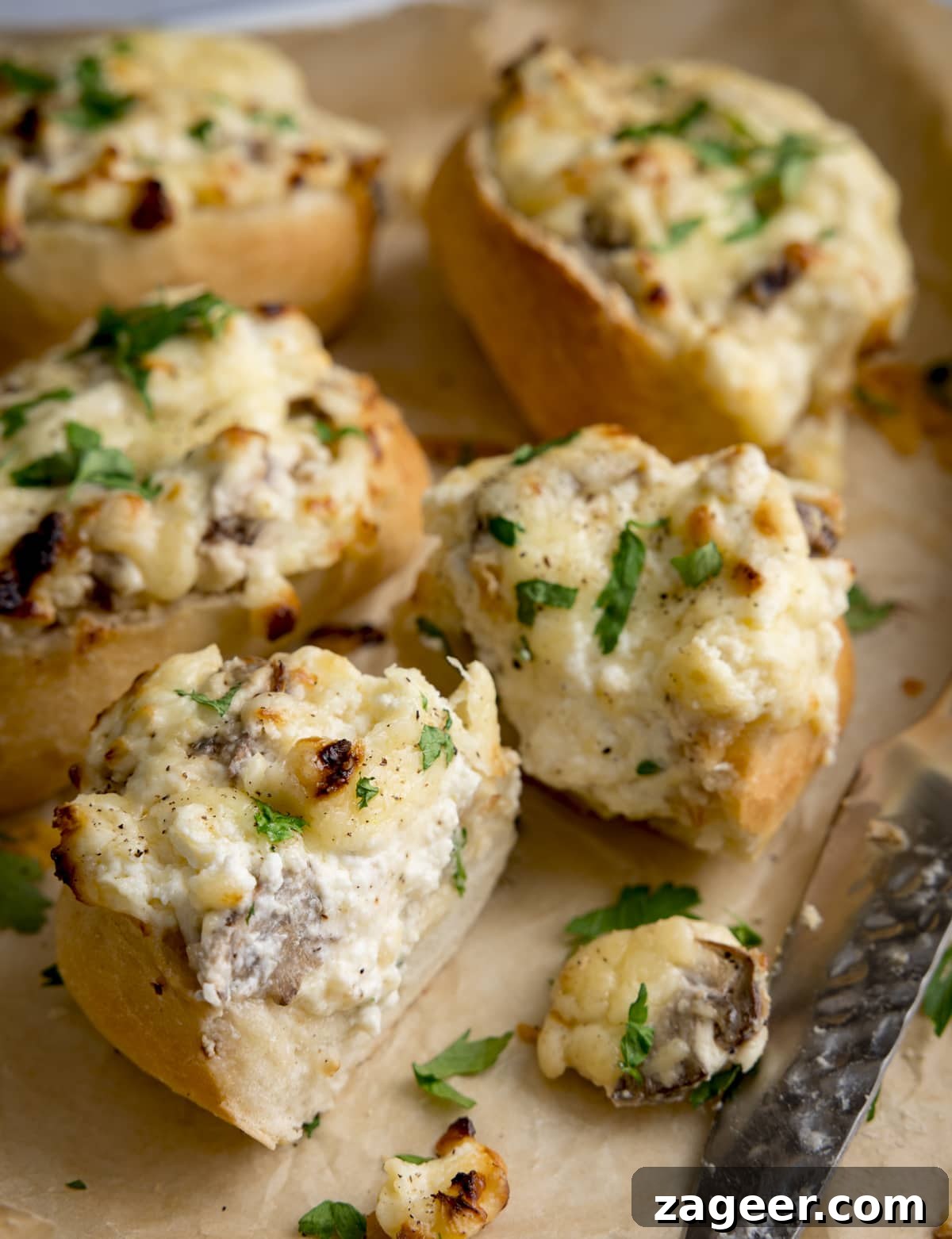 Creamy Garlic and Mushroom Stuffed Bread Rolls 4 Cheesy Mushroom Stuffed Garlic Breads topped with parsley on a tray. The stuffed bread closest to the front has been sliced in half.