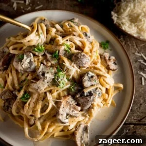 Creamy Mushroom Pasta Recipe with Garlic and Parmesan 12 a square shot of creamy mushroom pasta on a white plate with a spoon dug in