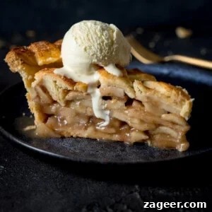 Ultimate Deep-Dish Apple Pie Recipe for Perfect Crust and Filling 9 A grey plate with a slice of deep dish apple pie on top with a scoop of vanilla ice cream on the top with a napkin and fork in the background on a grey table.