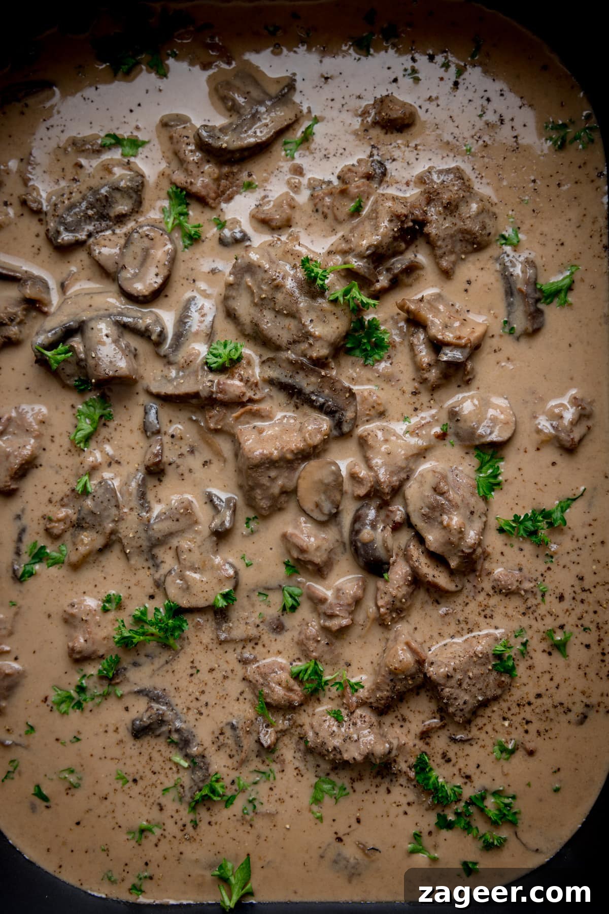 Overhead close up of slow cooker beef stroganoff with parsley sprinkled on top.