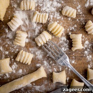 Authentic Homemade Potato Gnocchi Recipe for Fluffy Results 7 Gnocchi being cut and shaped on a wooden board. There is a fork in shot - used for rolling