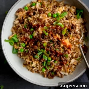 Square image of a bowl of minced beef fried rice, topped with sliced spring onions.