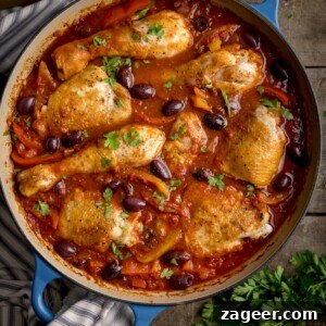 Classic Chicken Cacciatore Recipe: Rustic Italian Hunter’s Chicken 7 Overhead square image of chicken cacciatore in a large, shallow blue casserole dish. The dish is on a wooden table, next to some fresh herbs.