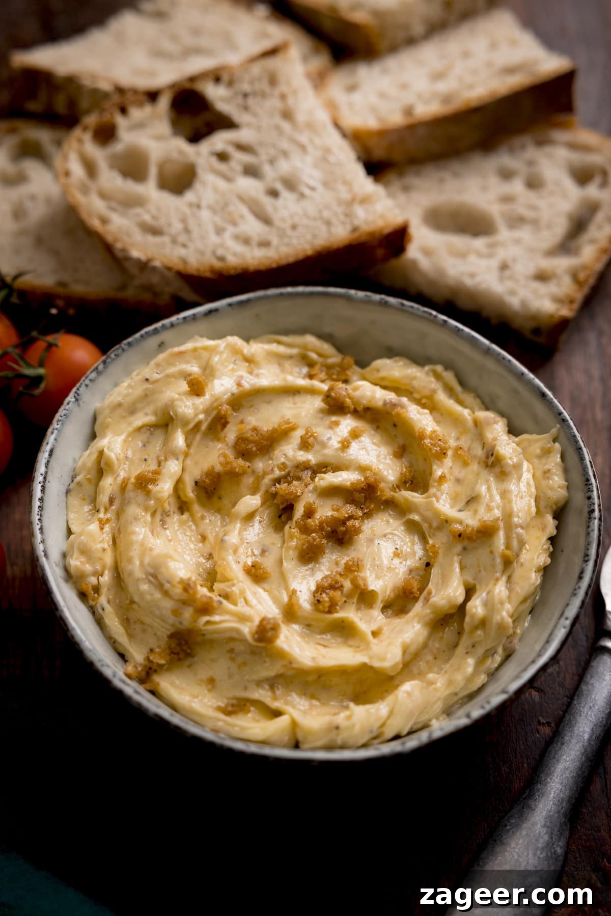 Crispy Chicken Skin Cracklings with Savory Butter Dip 2 Close up of a bowl of chicken skin butter with slices of bread in the background.