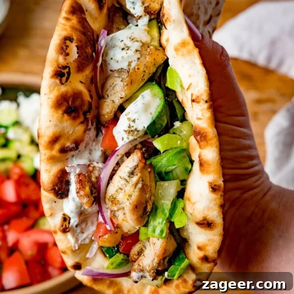 Crispy Chicken Skin Cracklings with Savory Butter Dip 16 A hand holds a toasted flatbread filled with chicken souvlaki