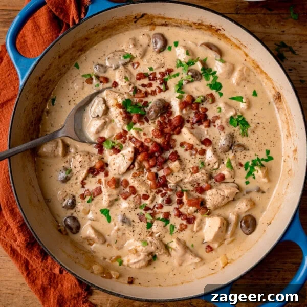 Crispy Chicken Skin Cracklings with Savory Butter Dip 20 A blue cast iron pan filled with chicken in a cream-cider sauce