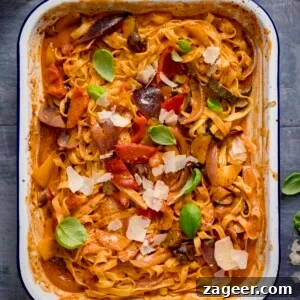 Roasted Veggie Pasta with Garlic and Parmesan 11 Square image of a white roasting tin filled with tagliatelle in a creamy roasted vegetable sauce on a blue background.
