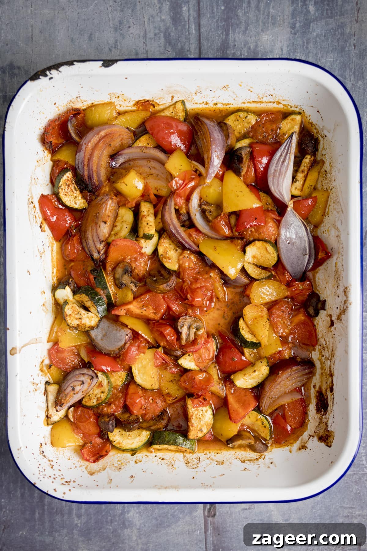 Roasted Veggie Pasta with Garlic and Parmesan 6 Overhead of a white tray filling with chopped roasted vegetables on a blue background.