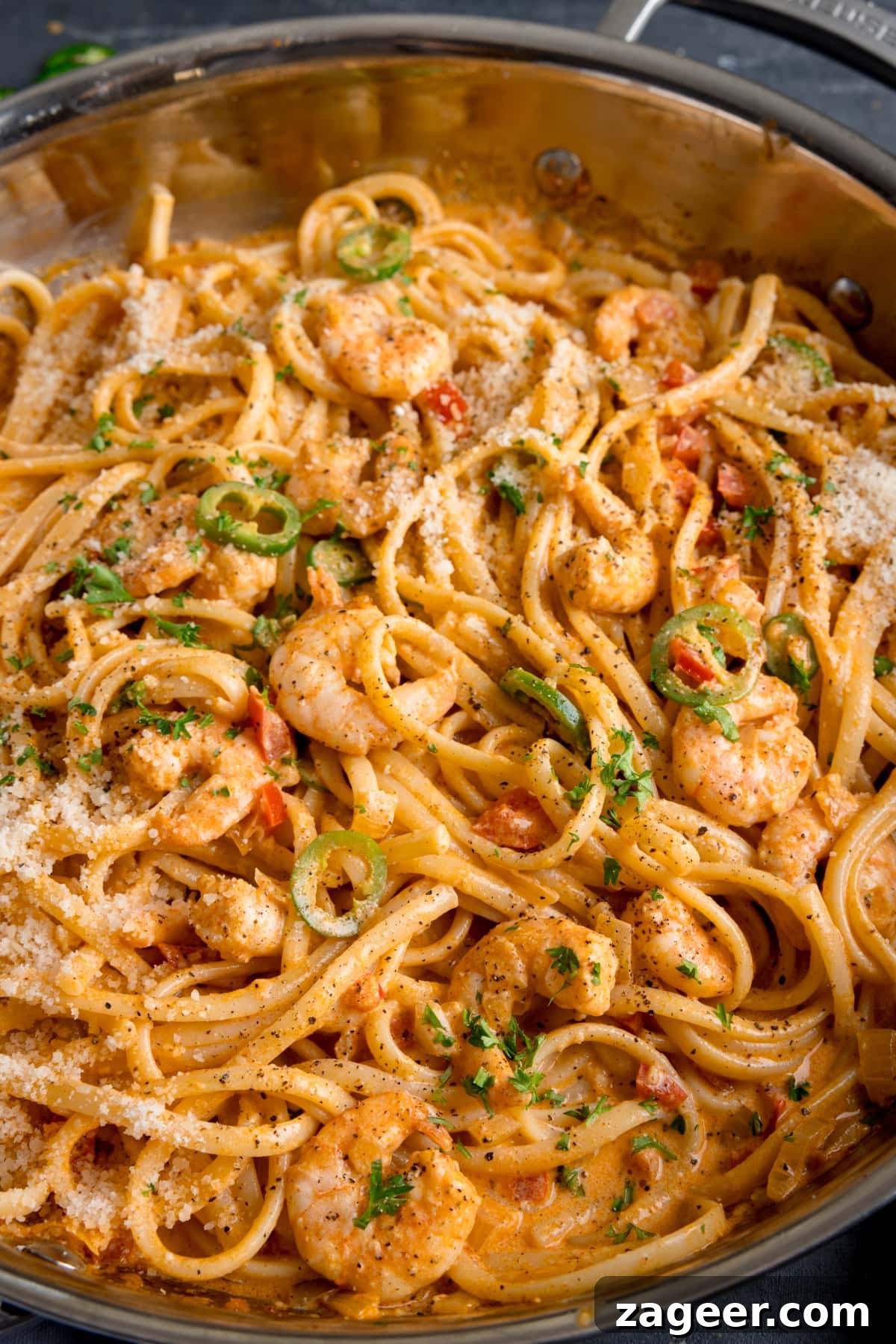 Creamy Cajun Shrimp Pasta Recipe — Quick Spicy Dinner 5 Tall close-up image of a pan of prawn linguine in a creamy buffalo sauce.