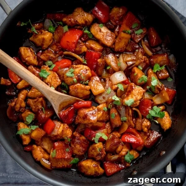Spicy Honey-Glazed Chicken Recipe 10 Overhead image of Sticky Pineapple Chicken Stir Fry in a pan. There is a wooden spoon sticking out of the pan.