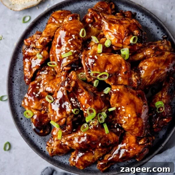 Spicy Honey-Glazed Chicken Recipe 14 A plate of tamarind chicken wings glazed to perfection, garnished with sliced spring onions and sesame seeds.
