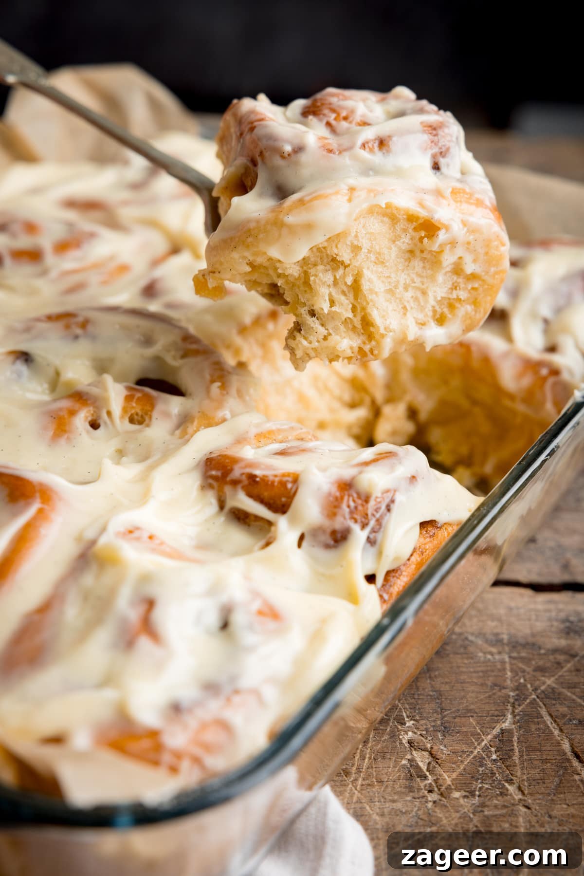 Fluffy Cinnamon Rolls Recipe for Soft, Homemade Swirls 9 A glass baking dish of frosted cinnamon rolls with one cinnamon roll being taken out on a fork.
