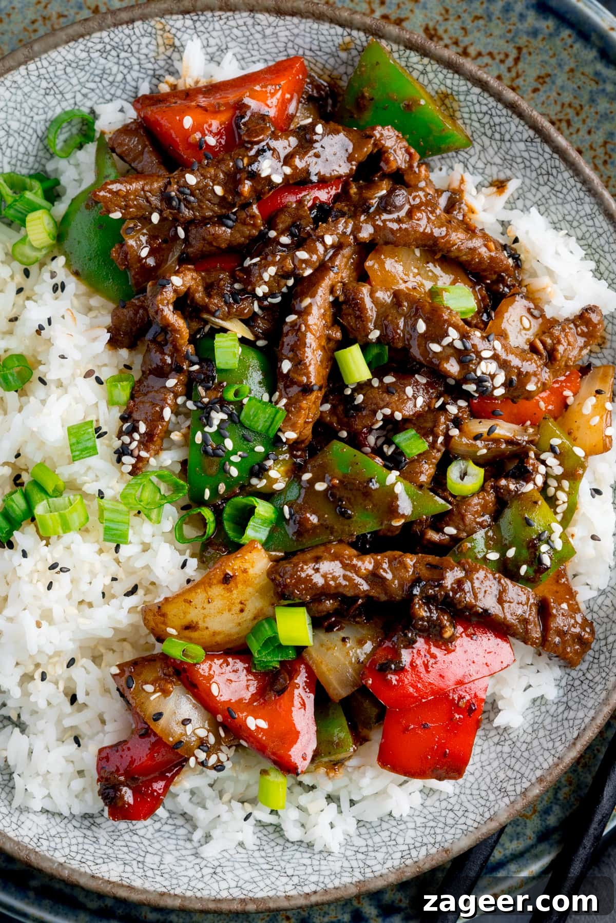 Authentic Black Bean Sauce Recipe for Stir-Fries and Marinades 7 Beef in black bean sauce stir fry with boiled rice in a bowl, topped with spring onions and sesame seeds.