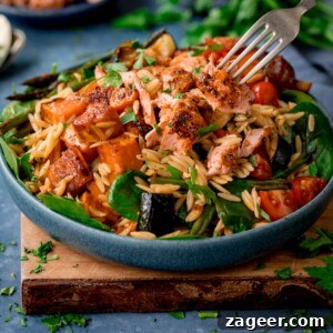 Lemon-Dill Salmon Orzo Pasta Salad for Weeknight Meals 7 A blue bowl full of orzo pasta salad with salmon on a wooden chopping board.