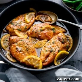 Square image of a dark pan filled with honey lemon chicken.