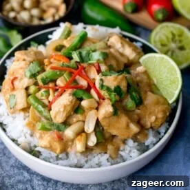 Bowl of rice topped with peanut butter chicken with green beans, chillies and coriander (cilantro)