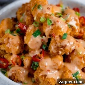 Bang Bang Chicken in a white bowl topped with chillies and spring onions