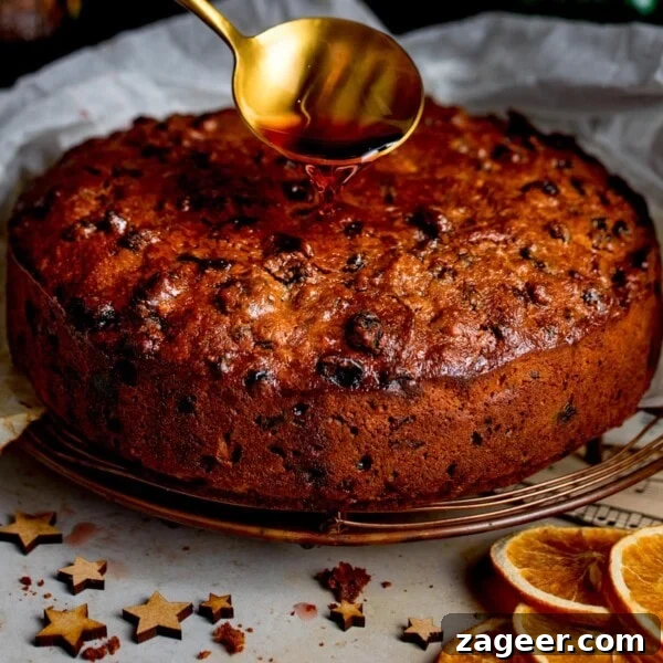 Christmas Cake Decorating Ideas for a Festive Finish 12 Cherry brandy being spooned onto a christmas cake with orange slices and wooden stars in the foreground.
