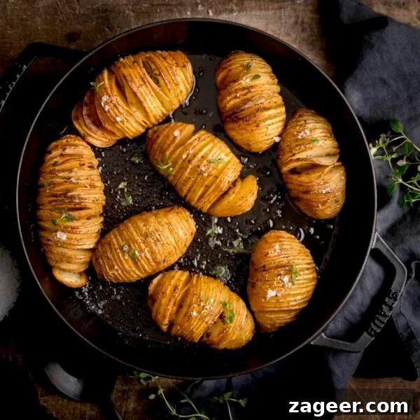 Creamy Duchess Potatoes Recipe for Perfect Sides 5 Hasselback potatoes in a black cast iron pan on a wooden table next to a dark grey napkin.