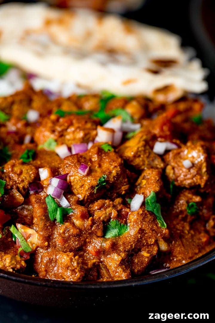 Low-Fat Slow-Cooked Spicy Beef Curry Recipe 7 Close up of slow cooked beef curry with coriander and red onion on top