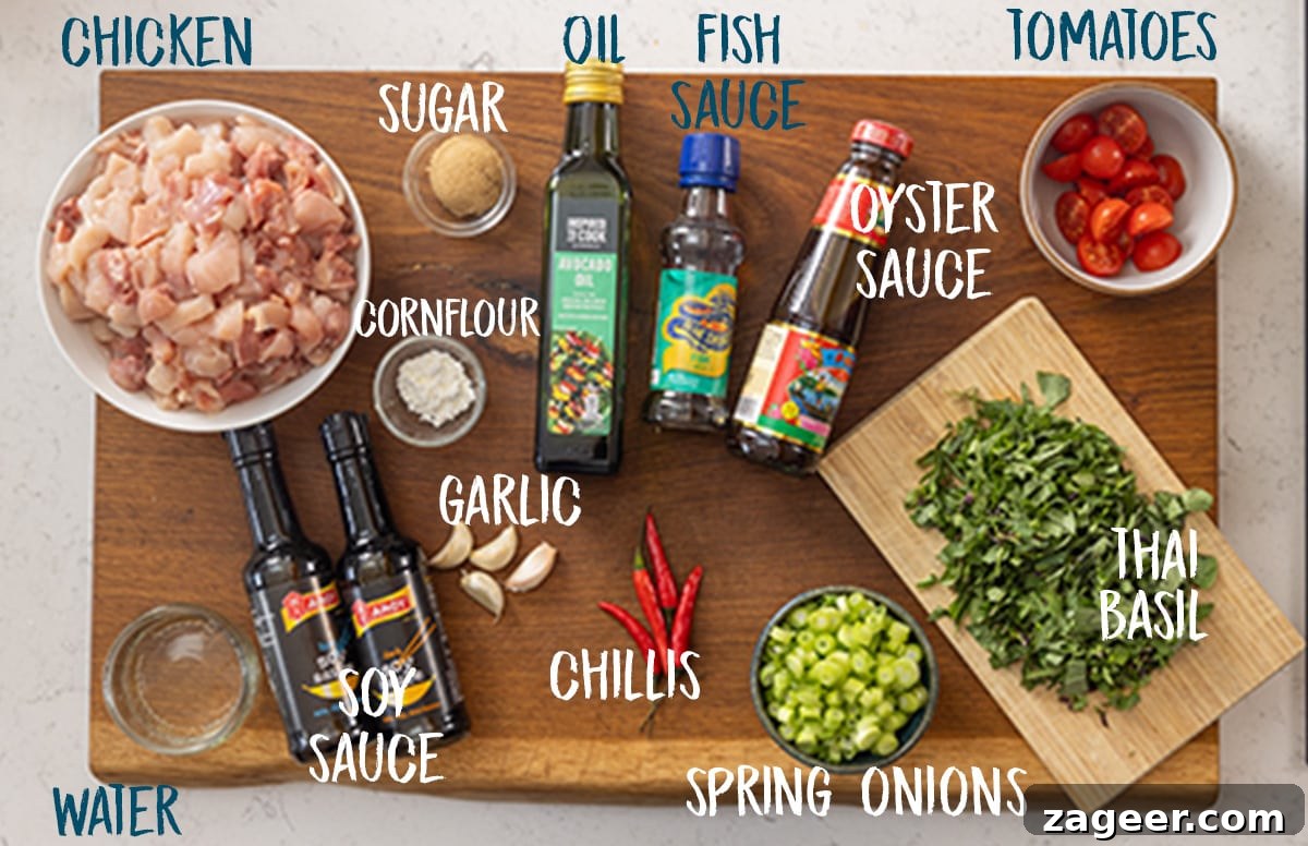 A wide overhead image of the ingredients for thai basil chicken on a wooden cutting board, which is on a white marble surface. The ingredients are labelled in white, except where some ingredient labels flow on top of the white surface, in which case they are blue.