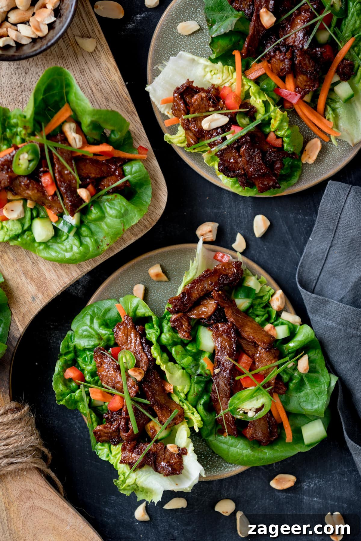 Picture of a plate with two Korean beef lettuce wraps with another plate and board with more lettuce wraps in the background.