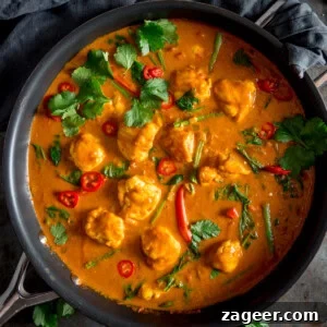 Creamy Monkfish Coconut Curry Recipe for Flavorful Dinner 12 A square overhead shot of Monkfish Coconut Curry in a grey pan, topped with coriander. On a grey surface with a grey napkin in the background.
