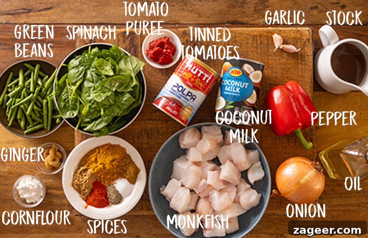 Creamy Monkfish Coconut Curry Recipe for Flavorful Dinner 3 An overhead shot of the ingredients in Monkfish Coconut Curry laid out on a wooden board. The ingredients are labelled in white, they are as follows: tomato puree, tinned tomatoes, coconut milk, monkfish, spices, cornflour, ginger, green beans, spinach.
