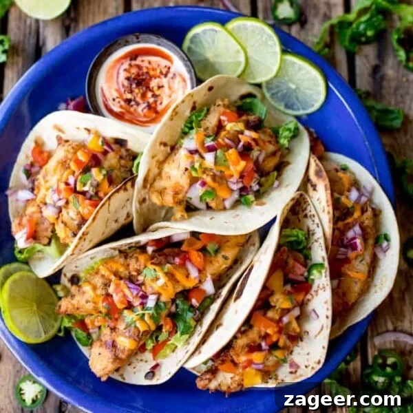 Crispy Beer-Battered Fish Recipe for Perfect Fried Fish 11 Overhead square image of 6 crispy fish tacos on a blue plate, topped with pico de gallo and sriracha mayo.