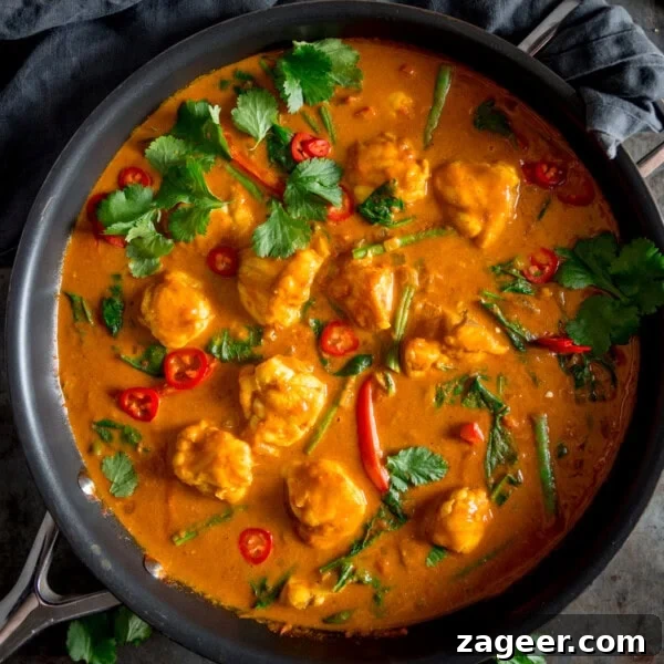 Crispy Beer-Battered Fish Recipe for Perfect Fried Fish 12 A square overhead shot of Monkfish Coconut Curry in a grey pan, topped with coriander. On a grey surface with a grey napkin in the background.
