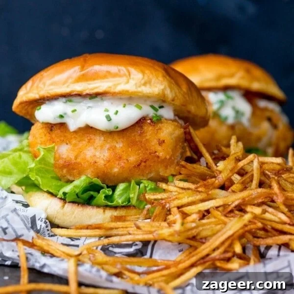 Crispy Beer-Battered Fish Recipe for Perfect Fried Fish 8 Breaded haddock burger on brioche bun with lettuce and chive-speckled mayonnaise. Shoestring fries to the right of the burger. A second burger in background.