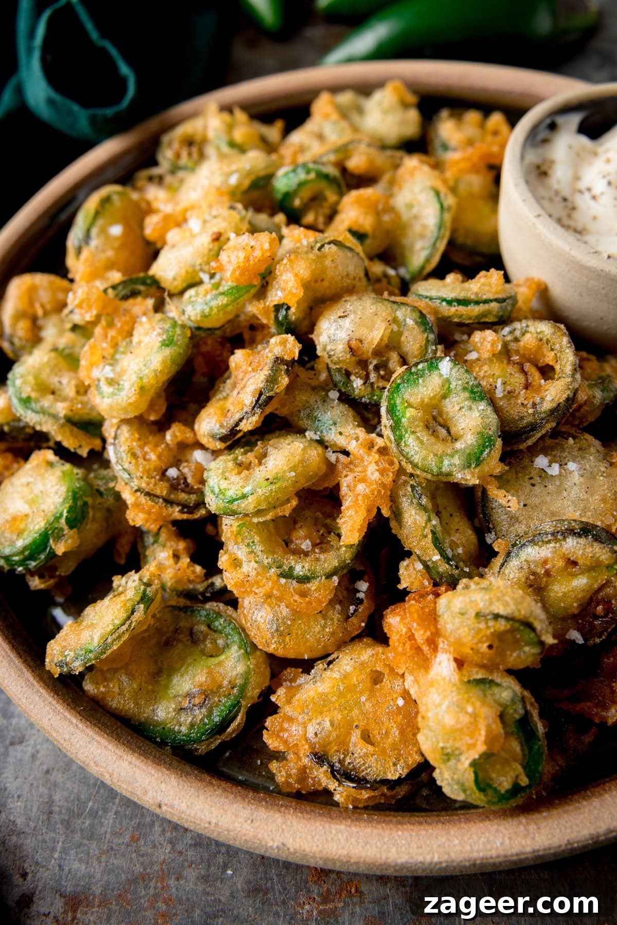 Crispy Fried Jalapeños: Spicy Crunch Snack Recipe 2 A tall image of a light brown bowl of fried jalapenos with garlic mayo.