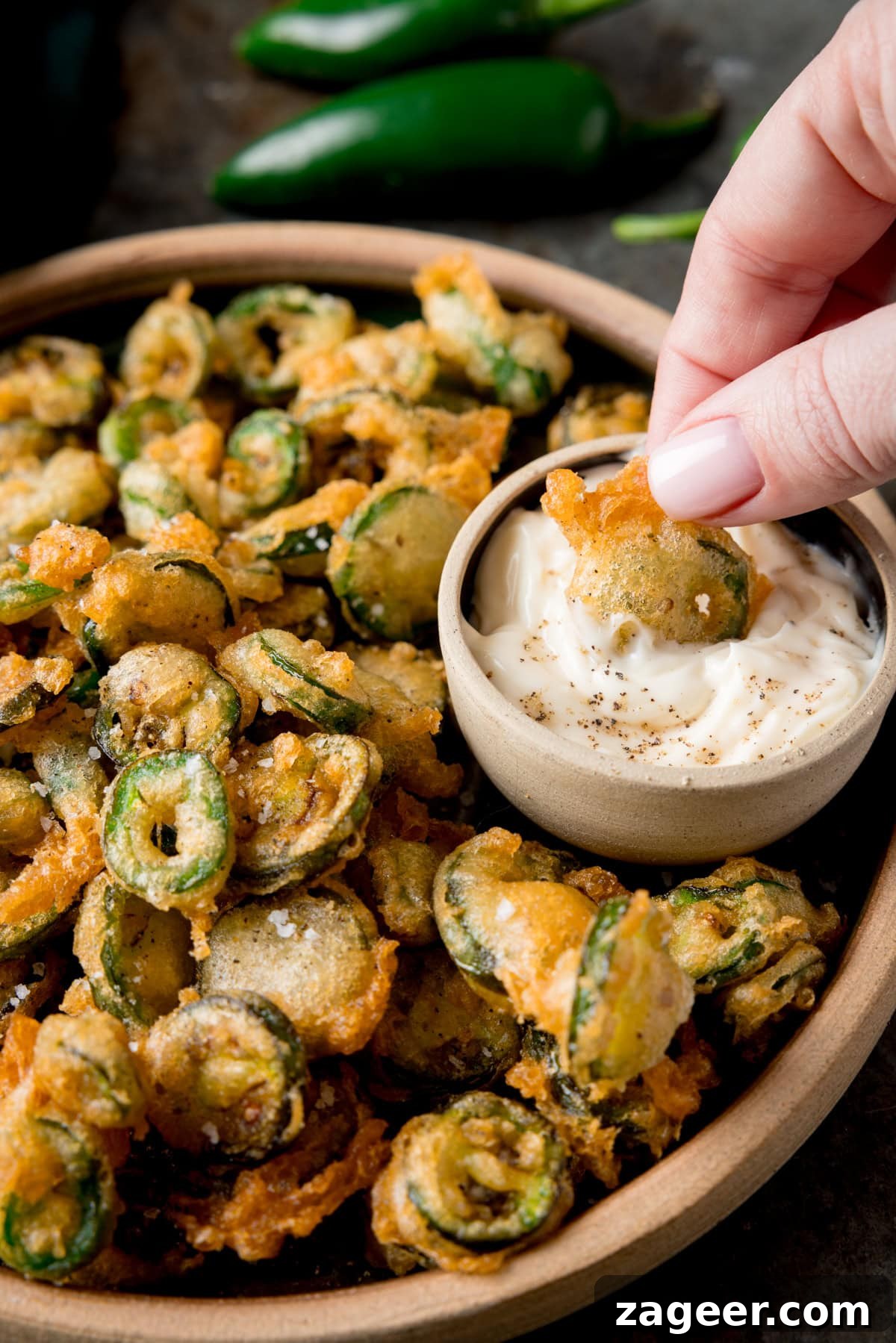 Crispy Fried Jalapeños: Spicy Crunch Snack Recipe 4 Fried jalapeno slice being dipped into garlic mayo.