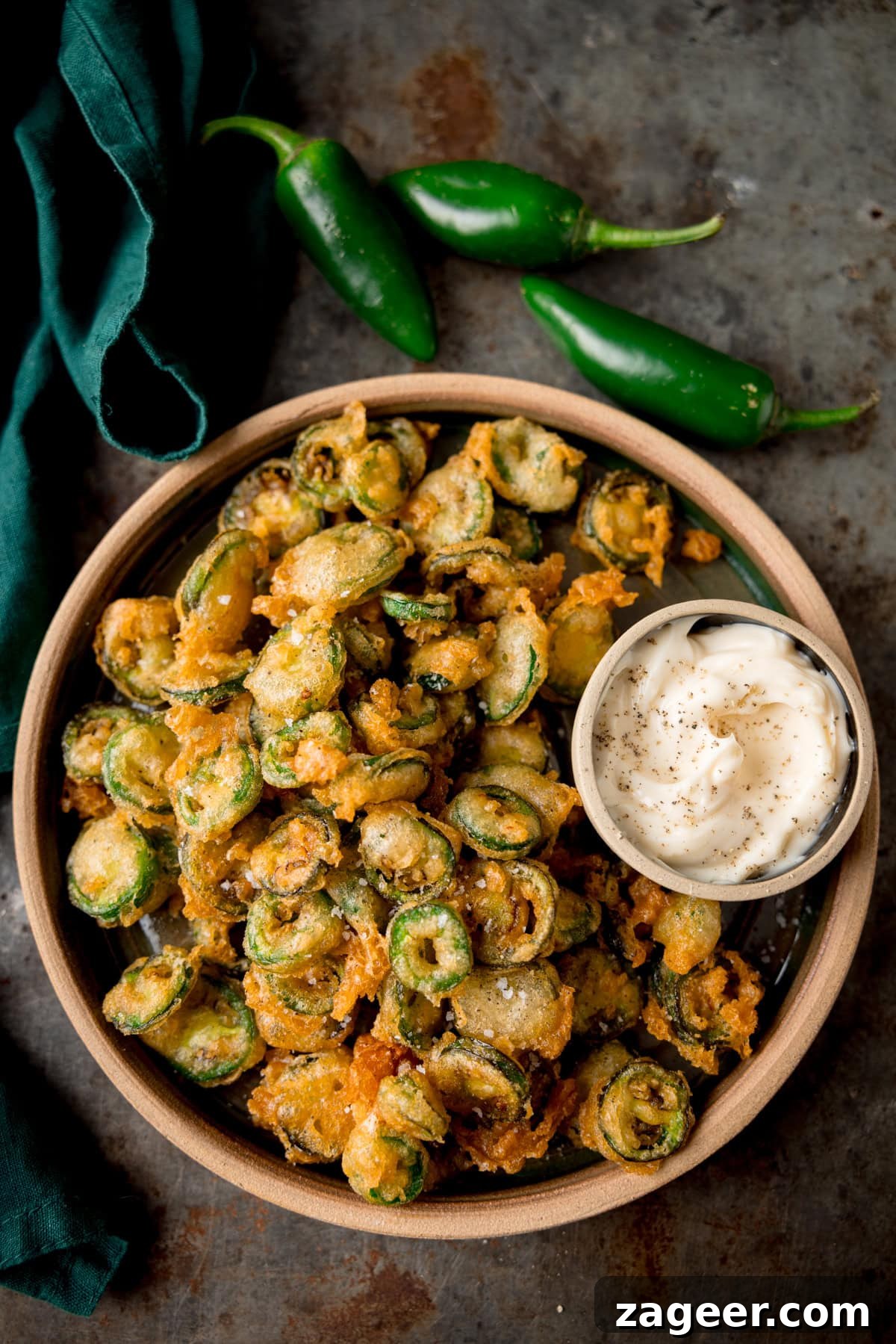 Crispy Fried Jalapeños: Spicy Crunch Snack Recipe 5 Bowl of fried jalapenos with garlic mayo and fresh jalapenos on the side.