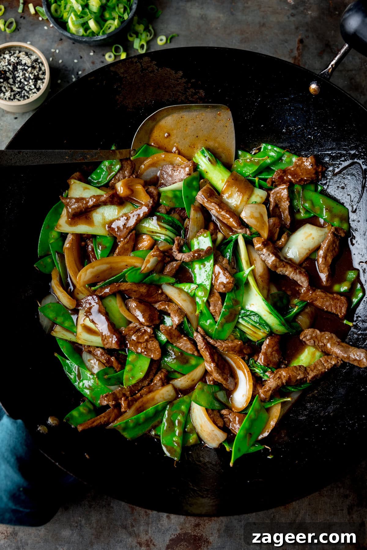 Quick and Flavorful Beef Stir-Fry with Garlic and Veggies 2 Beef Stir Fry in a black wok with a spatula, spring onions and sesame seeds nearby