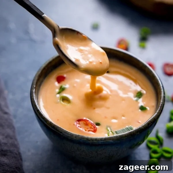 Authentic Caesar Salad Dressing Recipe You Can Make at Home 6 Spoonful of bang bang sauce being lifted from a bowl on a dark surface.