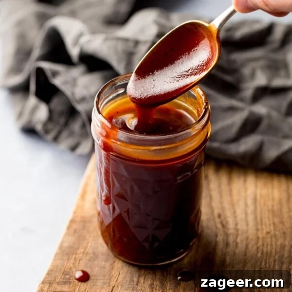 Authentic Caesar Salad Dressing Recipe You Can Make at Home 7 Spoonful being taken from a jar of homemade bbq sauce, sitting on a wooden board