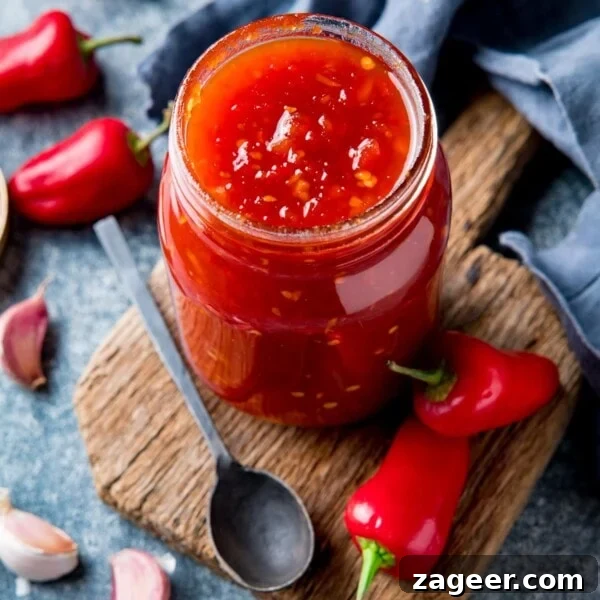 Authentic Caesar Salad Dressing Recipe You Can Make at Home 8 Overhead shot of sweet chilli sauce in a jar with chillies and garlic scattered around