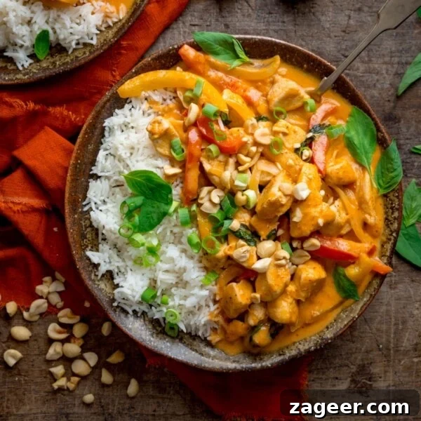Comforting Chicken and Potato Curry Recipe for Weeknight Dinners 6 Square overhead image of chicken panang curry and rice in a brown bowl, topped with chopped peanuts and Thai basil leaves.