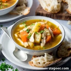 Piled High Chicken and Vegetable Soup with bread and spoon.