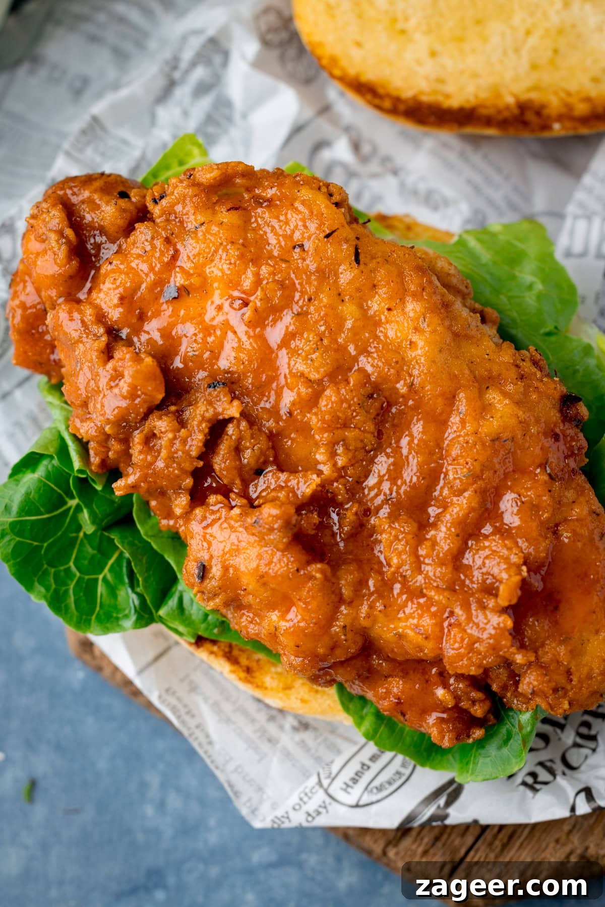 A tall, overhead image of a Buffalo Chicken burger with the top bun removed to show the chicken.