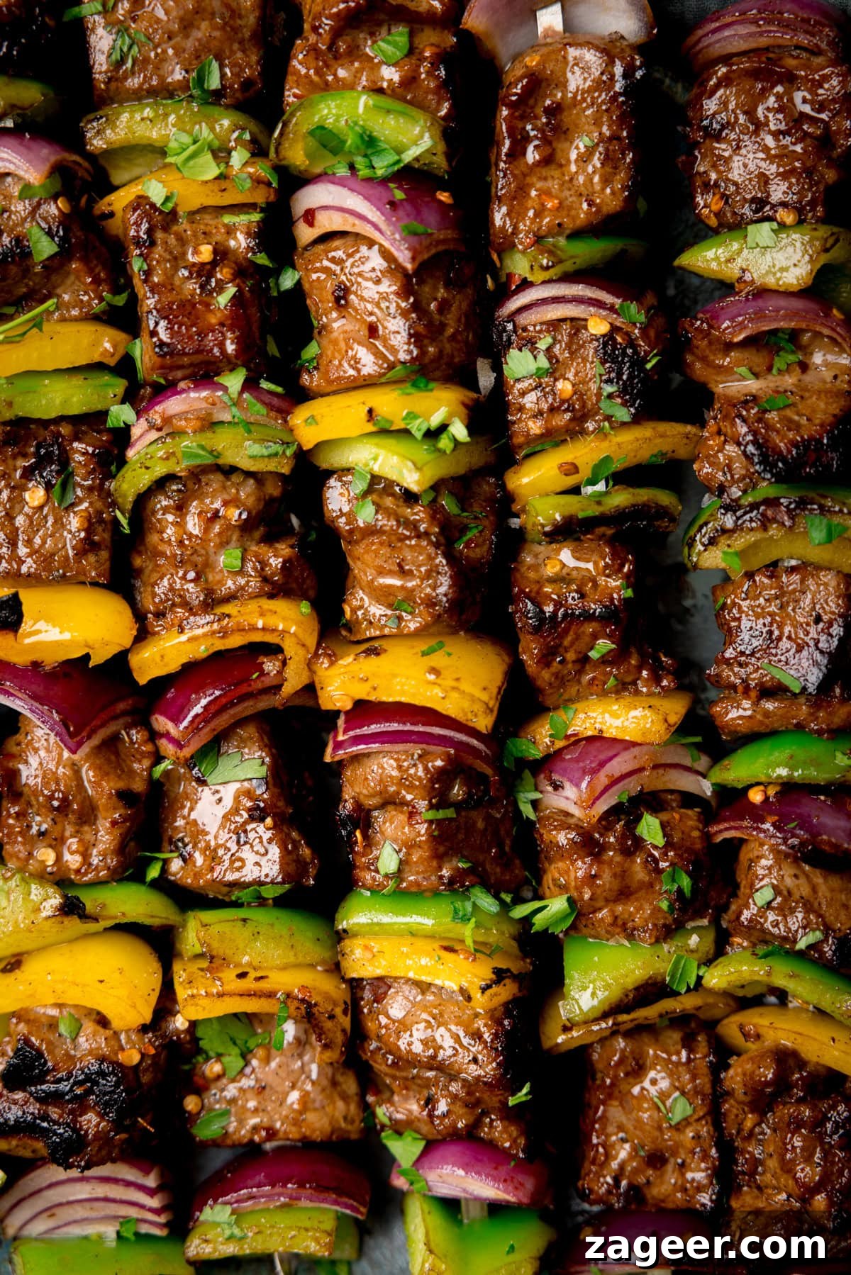 A tall closeup shot of five steak kebabs. The image shows five kebabs placed next to each other in a line, the image is so closeup that nothing else can be seen.