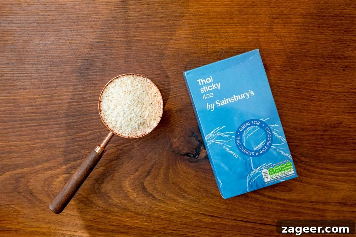 How to Make Perfect Thai Sticky Rice: Rice Cooker & Stovetop Methods 3 A wide, overhead shot of the ingredients for Thai Sticky Rice. The ingredients are laid out on a wooden cutting board. There is a box of dry sticky rice, and next to it a measuring cup filled to the top with the rice.