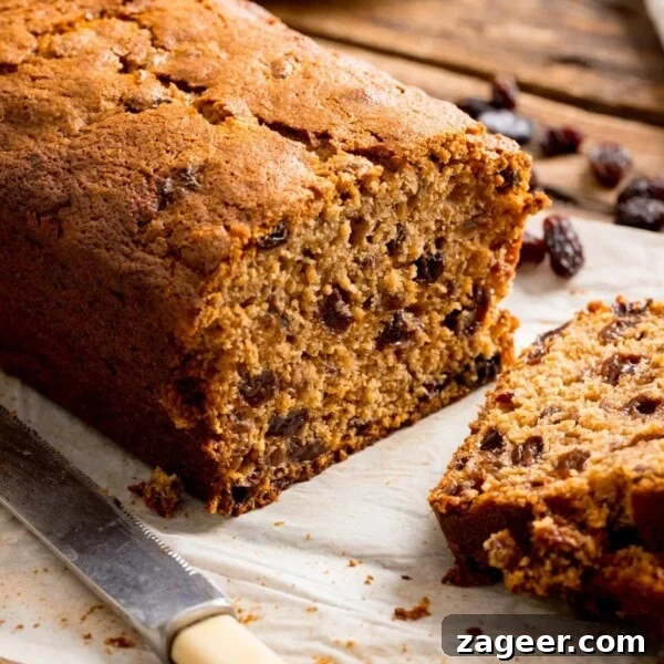 Raspberry White Chocolate Loaf Cake Recipe for Moist Dessert 8 Close up of a fruit tea loaf that has been sliced on a wooden table.