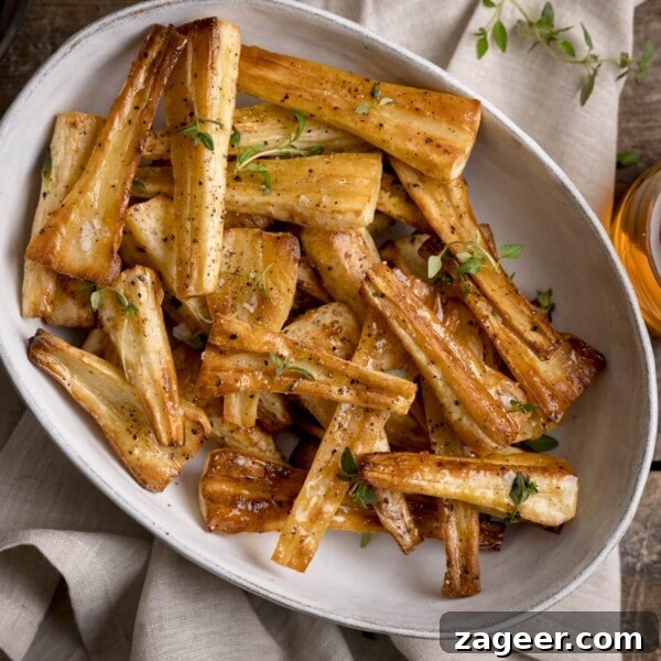 Make-Ahead Bacon Mashed Potato Casserole for Holiday Meals 9 Overhead image of Honey roast parsnips, topped with thyme leaves in a white oval bowl.