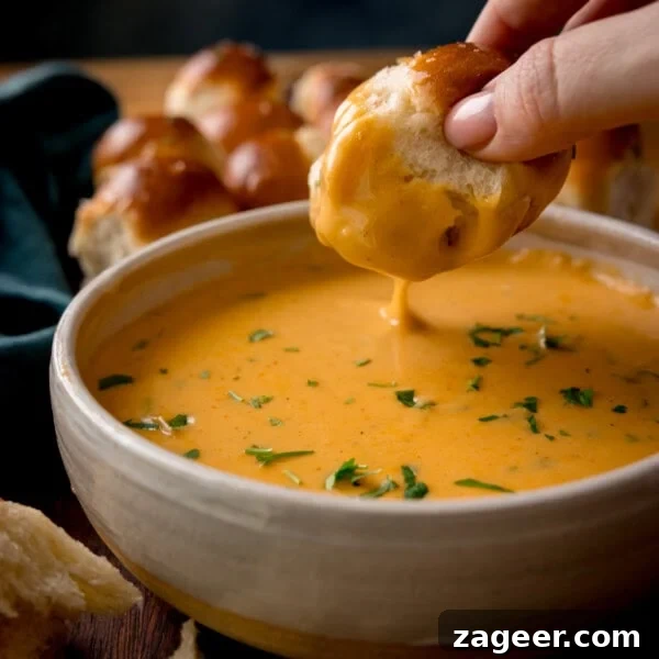 Cranberry and Brie Bites: Savory Holiday Appetizer Recipe 9 A hand dips a piece of bread into a bowl of creamy orange beer cheese dip.