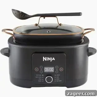 Slow Cooker Coconut Chicken Curry Recipe for Tender Meat 14 A black Ninja Slow Cooker with a control panel, a glass lid with gold handles, and a slotted serving spoon resting on top.