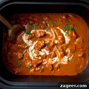 Slow Cooker Coconut Chicken Curry Recipe for Tender Meat 7 A square, overhead shot of Slow Cooker Chicken Curry in a rectangular, black slow cooker. The curry is topped with chopped coriander and there is a wooden spoon in the top left side of the dish.