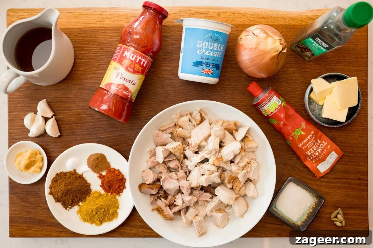 Leftover Turkey Curry Recipe: Flavorful Makeover for Leftovers 4 A wide, overhead shot of the ingredients for Leftover Turkey Curry. The ingredients are laid out on a wooden cutting board, which is placed on top of a white marble surface. The ingredients are as follows: leftover cooked turkey, onion, garlic, ginger, butter, oil, salt, garam masala, curry powder, paprika, cinnamon, chicken stock, passata, tomato puree, sugar, cardamom pods, and double cream.